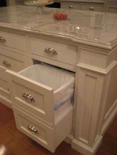 a white kitchen with marble counter tops and drawers