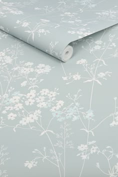 a blue wallpaper with white flowers and leaves on the side, in front of a gray background