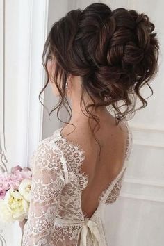 the back of a woman's head wearing a wedding dress and holding a bouquet