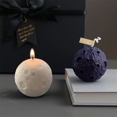 a candle that is sitting on top of a book next to a moon shaped candle