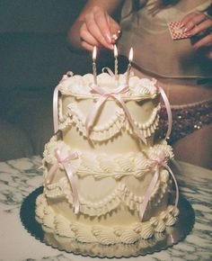 a woman lighting candles on top of a wedding cake