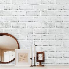 a white brick wall with a mirror, candles and pictures on the mantle next to it