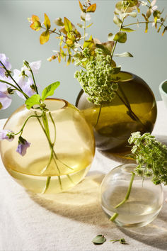 three vases with flowers in them sitting on a table