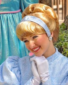 a woman in a blue dress is smiling at the camera and wearing a tiara