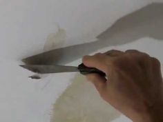 a person is using a pair of scissors to paint a wall with white paint on it