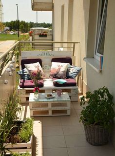 a balcony with two couches and some potted plants on the side walk way