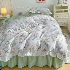 a bed with white and green comforter in a bedroom next to a night stand