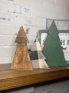 three wooden christmas trees sitting on top of a shelf