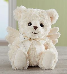 a white teddy bear with angel wings sitting on a table