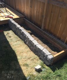 a garden bed made out of bricks in the back yard with grass growing around it