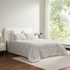 a bedroom with white walls and wood flooring has a leopard print comforter on the bed