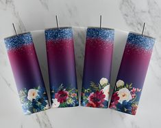 four candles with floral designs on them sitting on a marble surface