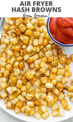 air fryer hash browns on a white plate with ketchup in the background