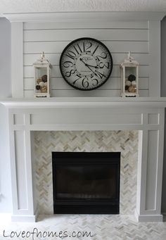 a white fireplace with a clock above it and candles on the mantel over the mantle