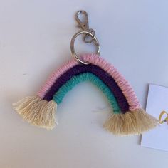 a rainbow keychain with tassels hanging from it's side on a white surface