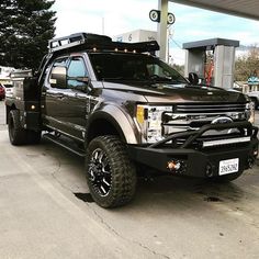 a large black truck parked in front of a gas station with lights on it's hood