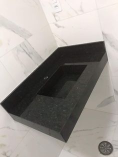 a black sink sitting on top of a white tiled bathroom floor next to a drain