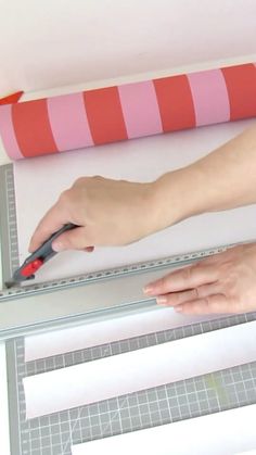 a woman is using scissors to cut out paper strips on a piece of construction material