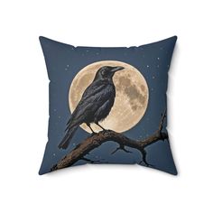 a black crow sitting on top of a tree branch with the moon in the background