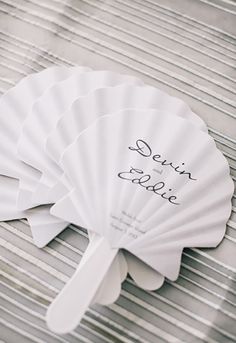 four white fan shaped fans sitting on top of a wooden table next to each other