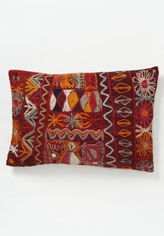 an orange and red decorative pillow on a white wall