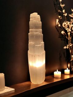 a tall glass vase sitting on top of a wooden table next to candles and flowers