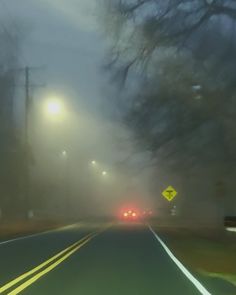 a foggy street with cars driving down it