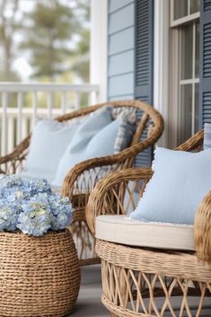 wicker chairs with blue pillows on the porch next to hydrangea flowers in a basket