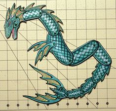 a drawing of a blue dragon on a cutting board with a ruler in front of it