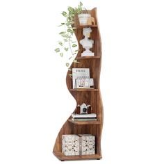 a wooden shelf with books, magazines and plants on it in front of a white wall