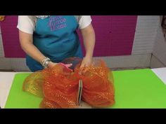 a woman in an apron is making something with orange ribbons on a green table top