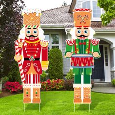 two wooden nutcrackers standing in front of a house with grass and flowers