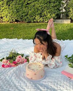 a woman laying on top of a blanket next to a cake