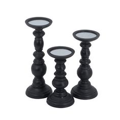 three black candlesticks sitting next to each other