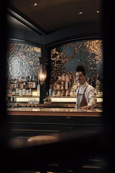 a man sitting at a bar with bottles behind him