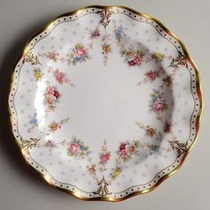 a white and gold plate with floral designs on the rim, sitting on a gray surface