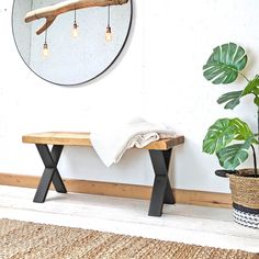 a wooden bench sitting in front of a mirror next to a potted plant on a rug