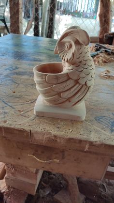 a clay owl cup sitting on top of a wooden table in the process of being carved