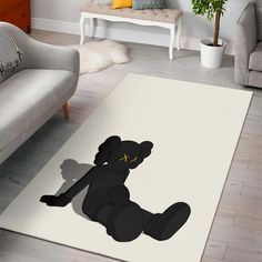 a living room area rug with a black teddy bear on it's side and a white couch in the background