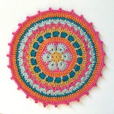 a colorful crocheted doily on a white wall