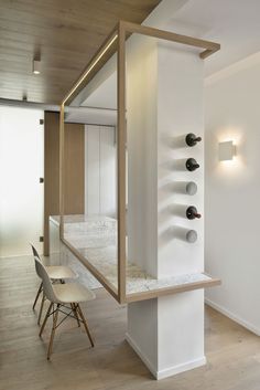 a room with a chair and shelves on the wall next to a table that has wine bottles on it