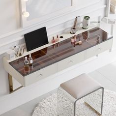 a desk with a laptop and other items on it in front of a wall mounted mirror