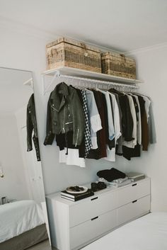 an organized closet with clothes and shoes hanging on the rack, next to a bed