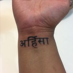 a wrist tattoo with the word buddha written in black ink, on a person's arm