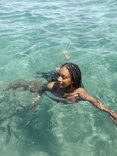 a woman swimming in the ocean with her hair tied back and braids hanging down