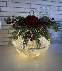 a glass bowl filled with flowers and greenery on top of a white countertop