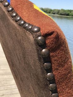 the back end of a bench with beads on it and a body of water in the background