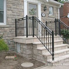 a black iron stair railing next to a brick house