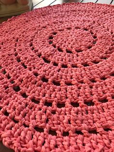 a pink crocheted rug on top of a wooden floor