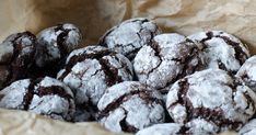 powdered chocolate crinkle cookies in a brown paper bag filled with powdered sugar